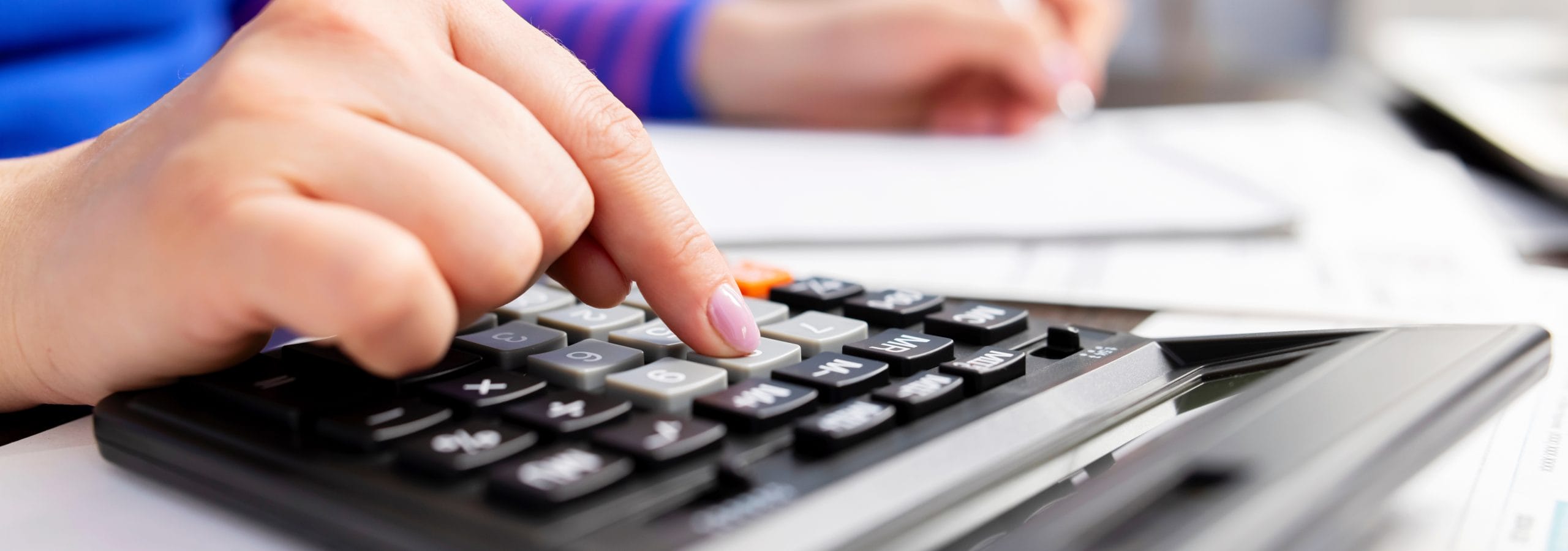 Woman using calculator for calculate taxes at home, doing paperwork