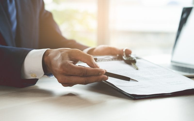 close up shots hands of client signing car lease form.