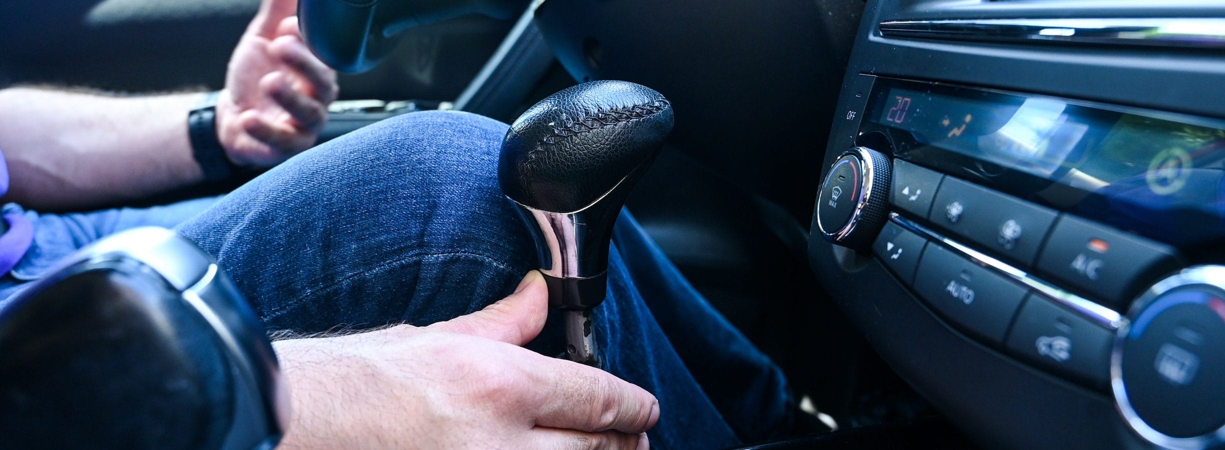 A man with a disability drives a car using hand controls for braking and acceleration in car.