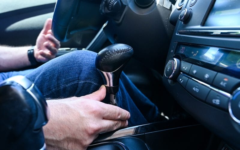 A man with a disability drives a car using hand controls for braking and acceleration in car.