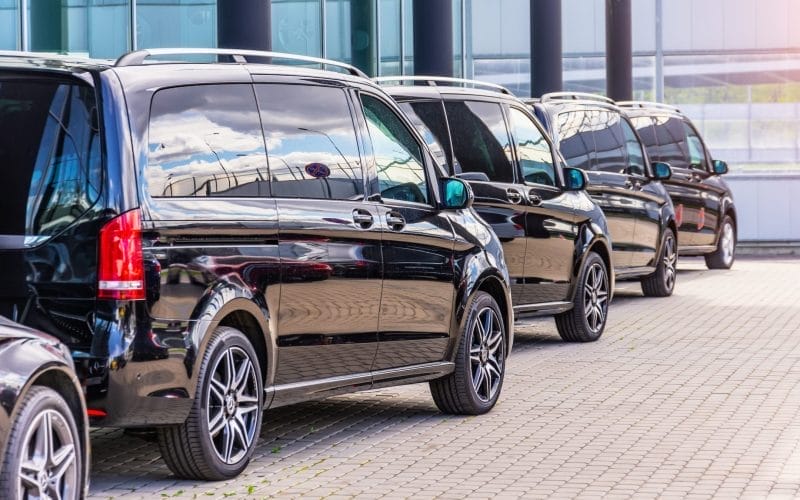 lineup of black minivans in a parking lot